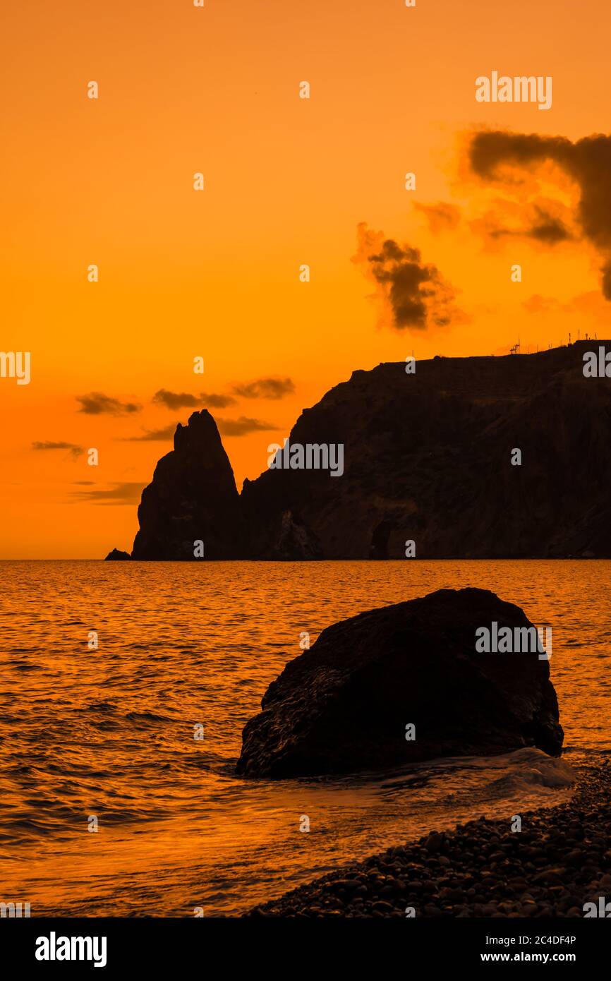 A red burning sunset with the silhouett of a cliff over the sea Stock ...