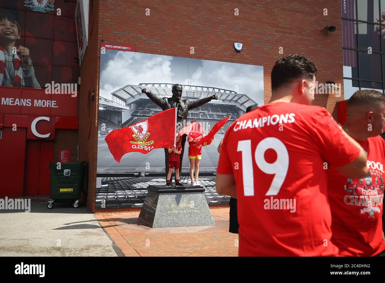 Liverpool fans pose for a photo with the Bill Shankly statue outside