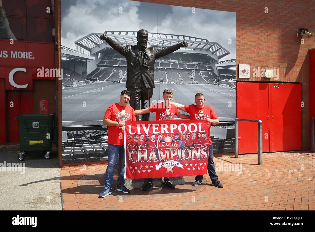 Liverpool fans pose for a photo with the Bill Shankly statue outside