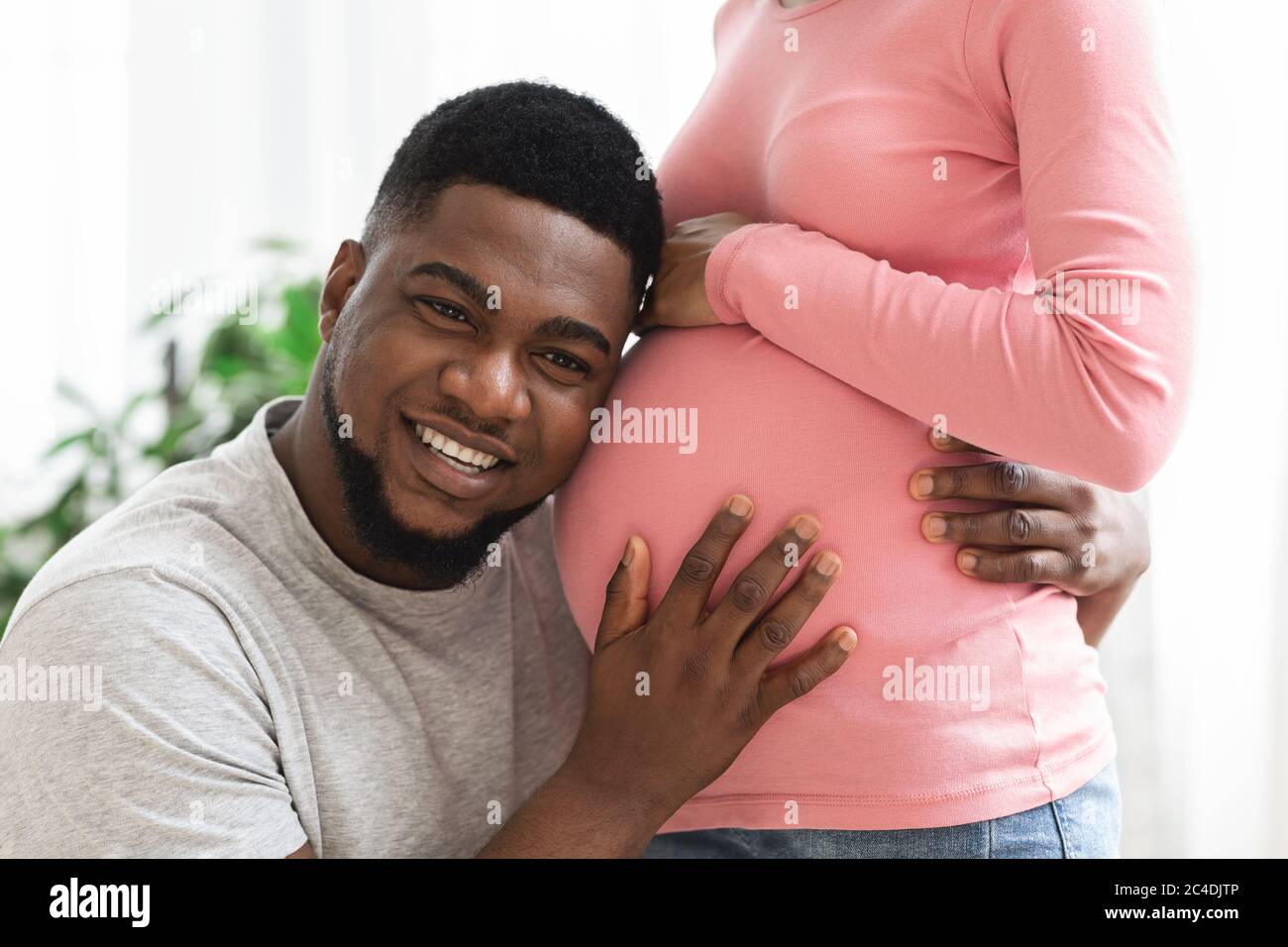 Closeup of man listening his happy pregnant wife belly Stock Photo - Alamy