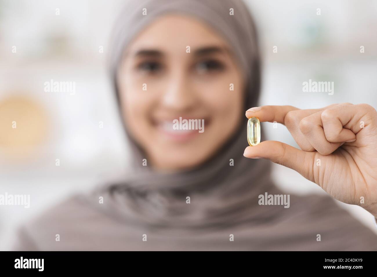 Vitamins And Food Supplements. Omega-3 Pill In Hands Of Smiling Arab Girl Stock Photo