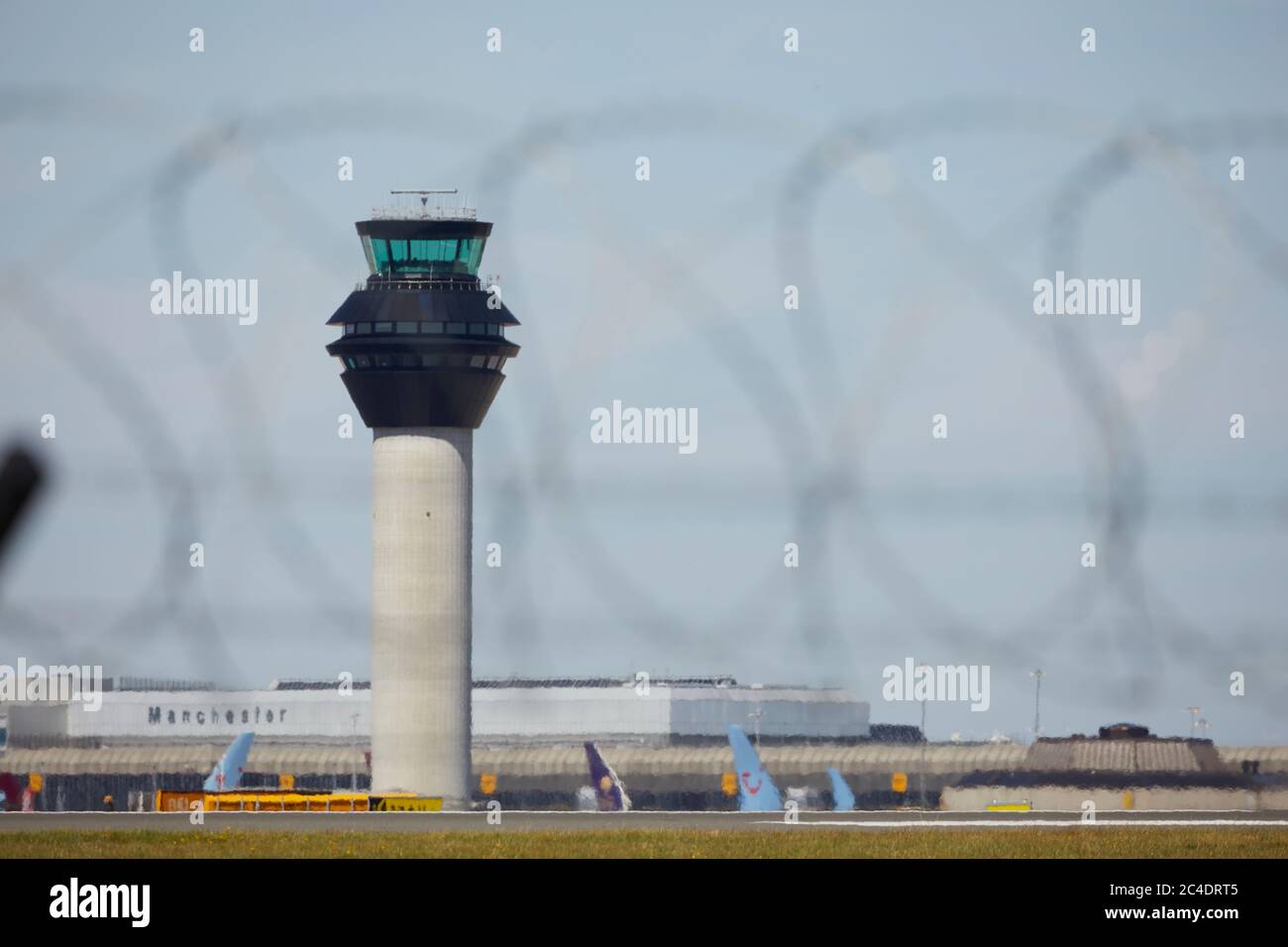 Manchester Airport air traffic control tower through barbed wire of the perimeter fence Stock Photo