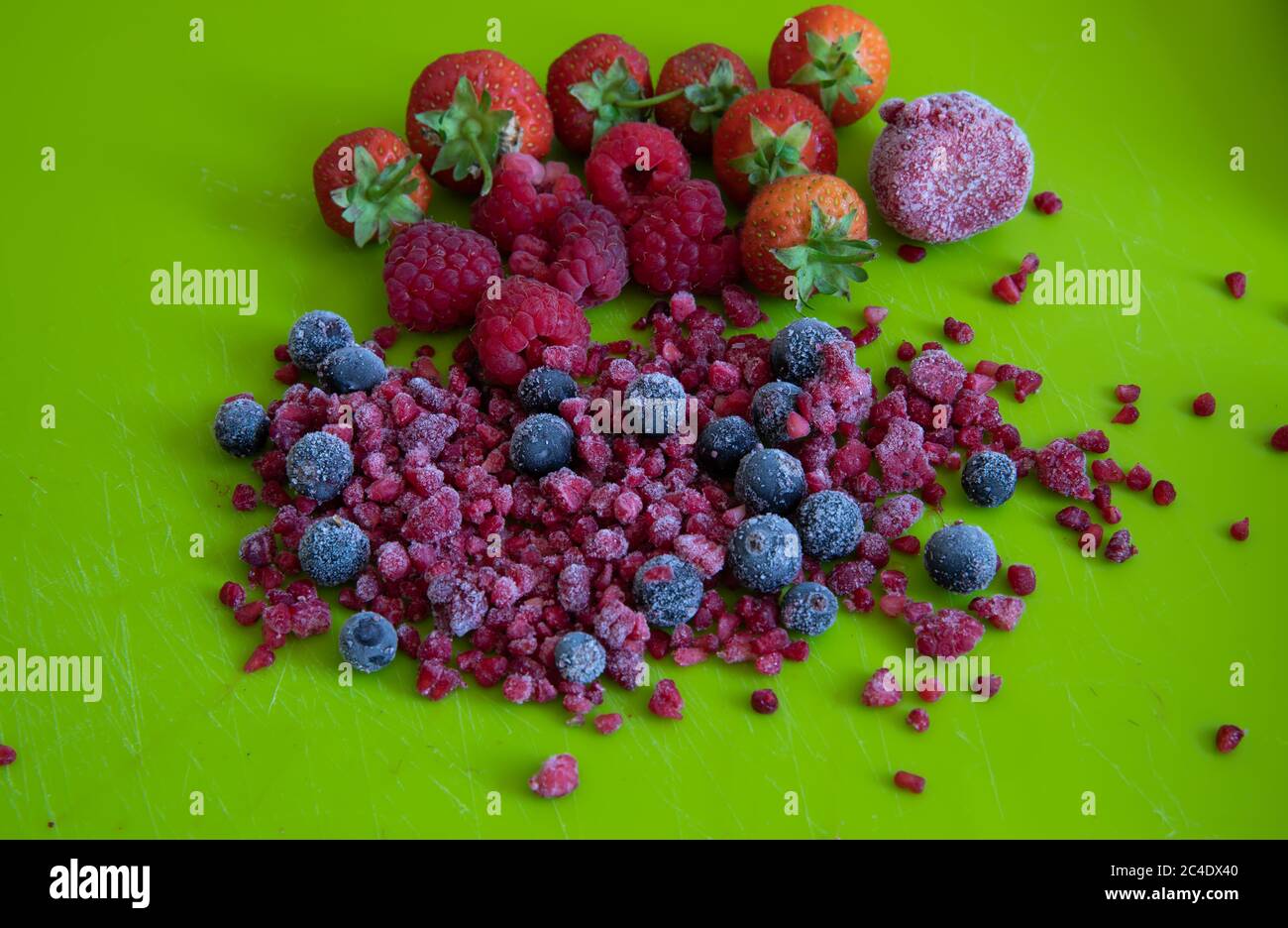 A selection of Fresh and frozen Fruits on a bright green chopping board Stock Photo