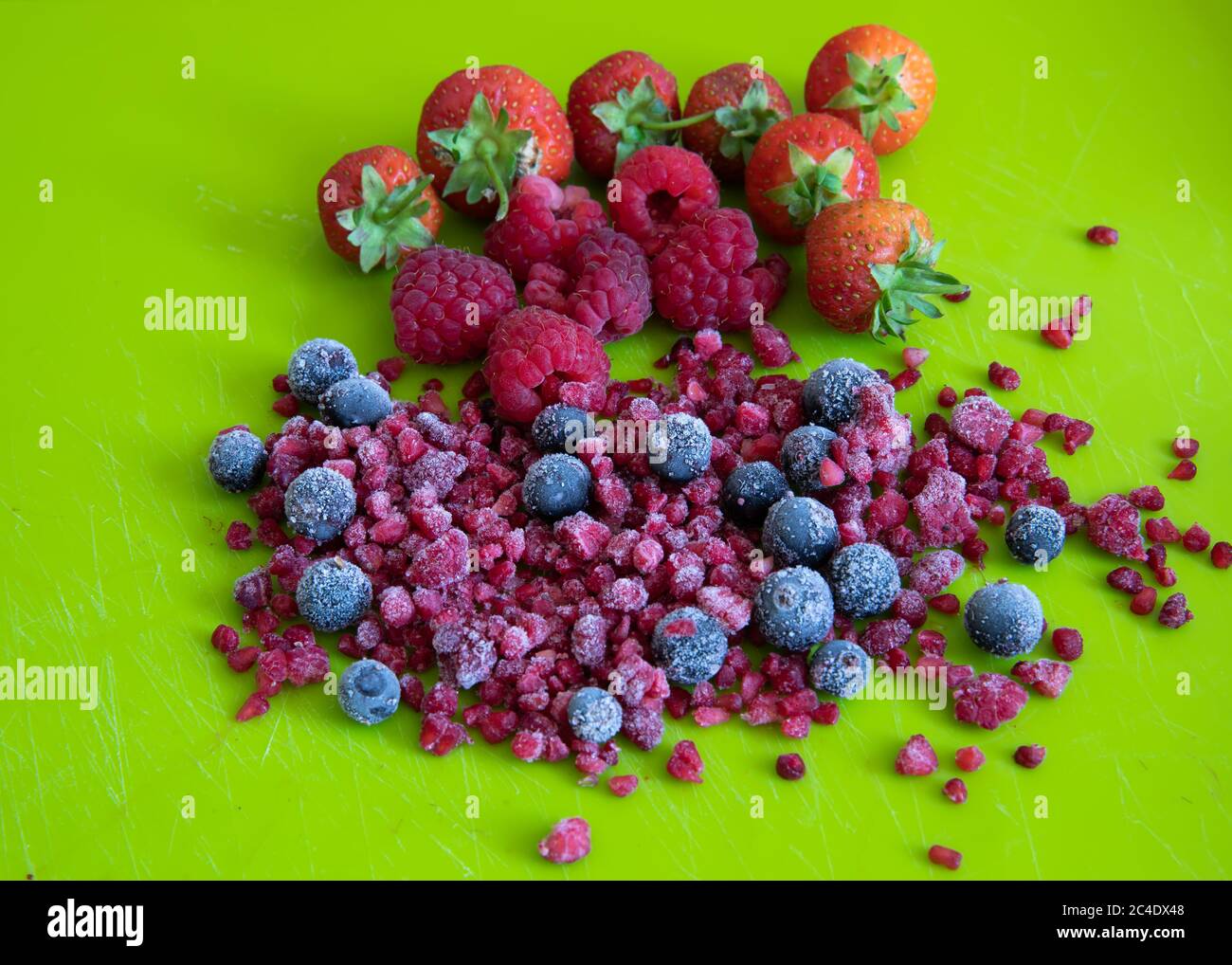 A selection of Fresh and frozen Fruits on a bright green chopping board Stock Photo