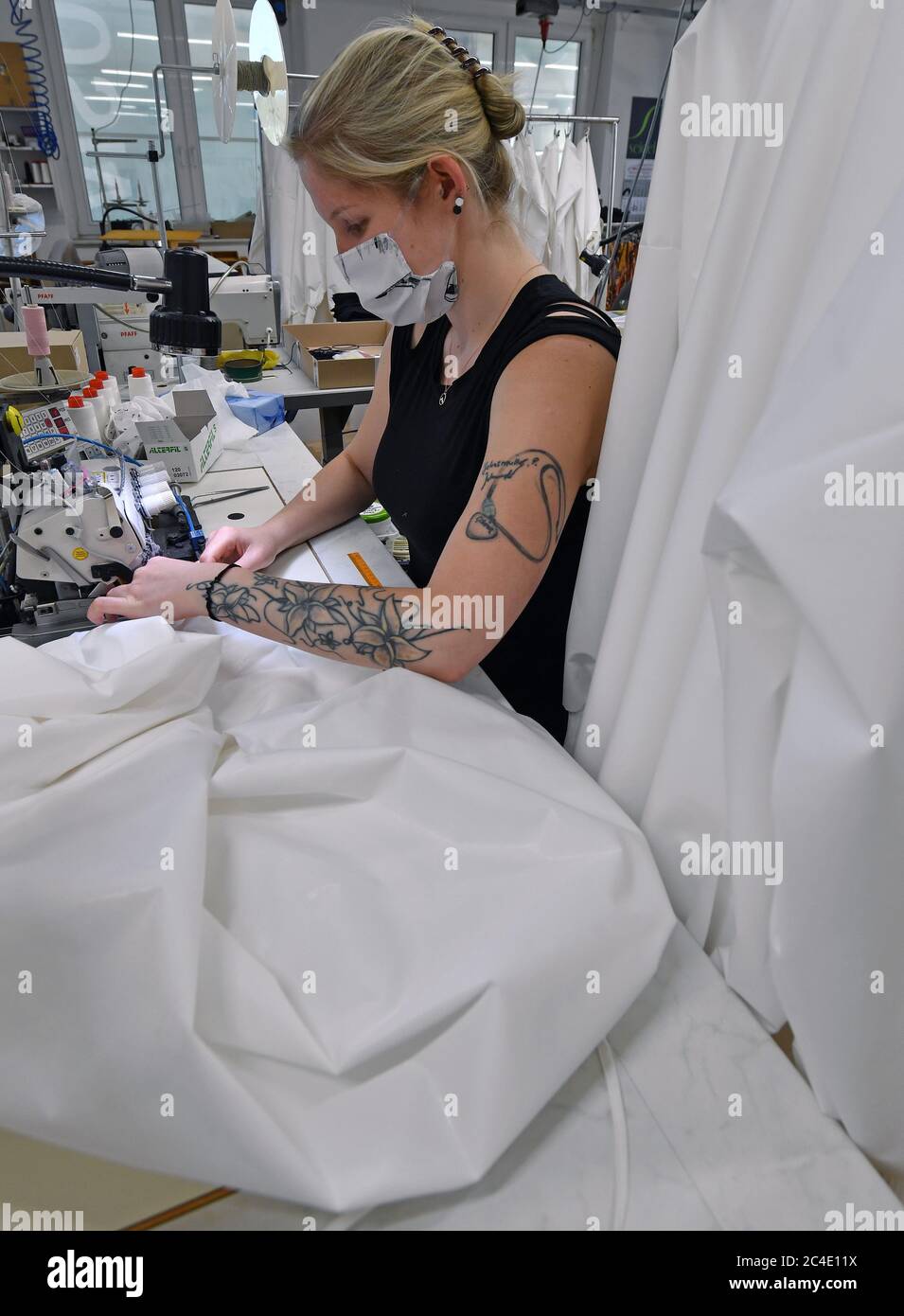 26 June 2020, Saxony, Schreiersgrün: Seamstress Anja Jahnsmüller makes  protective clothing in the sewing room of Seidel Moden. The Saxon textile  and clothing industry is campaigning for authorities and institutions to  rely