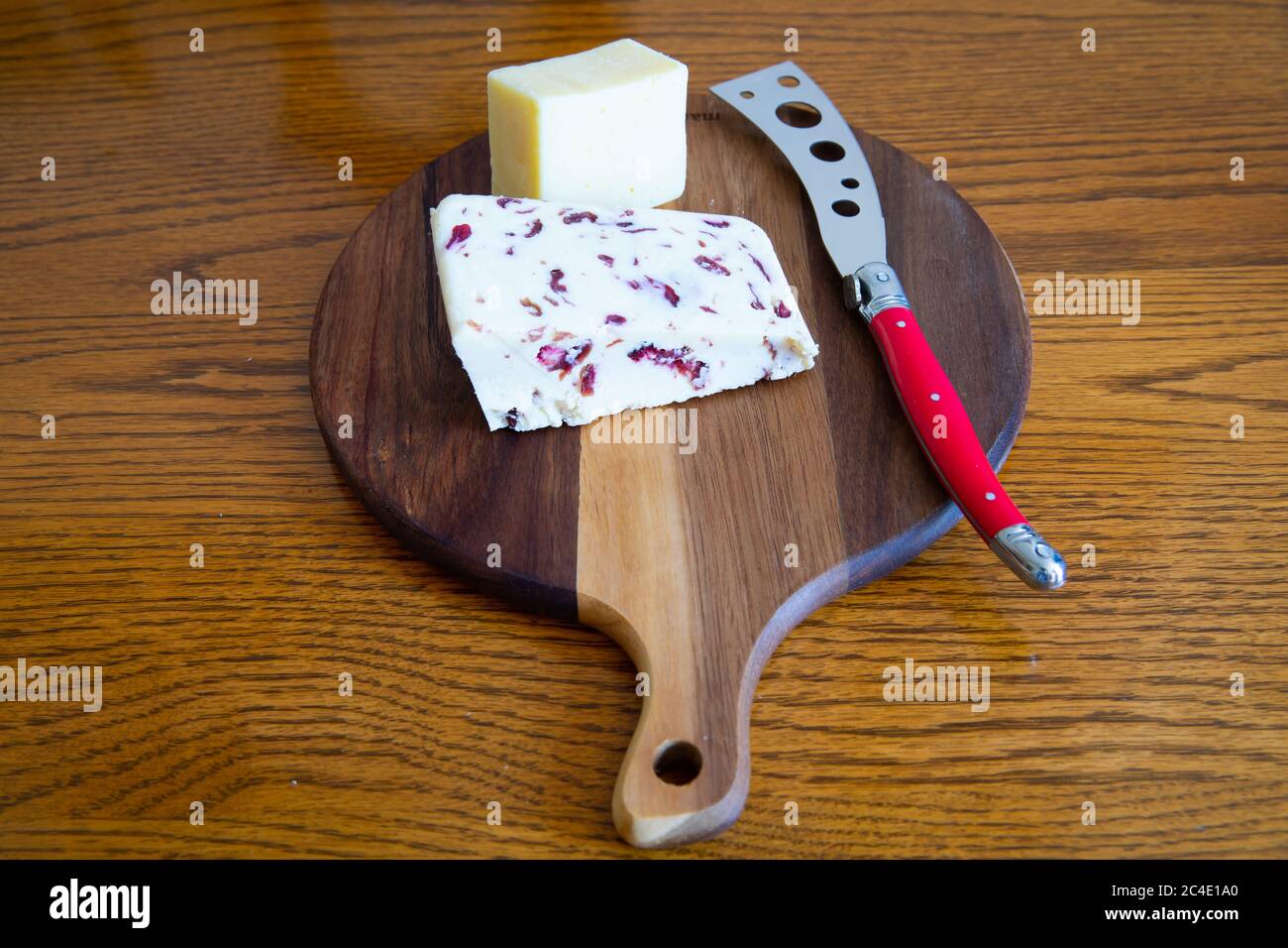 Fresh Cheese on a wooden cheeseboard with a red cheese knife Stock Photo