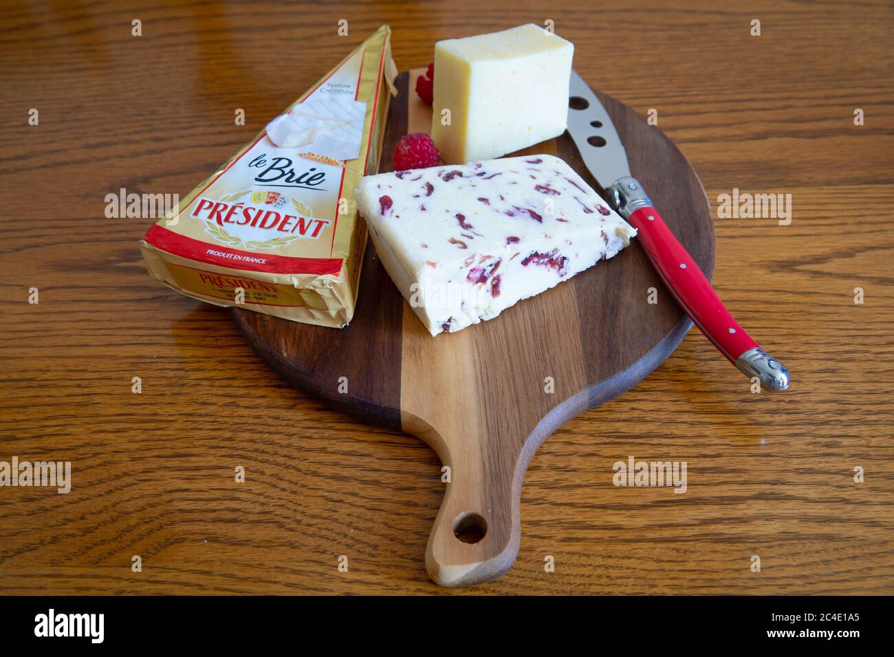 Fresh Cheese on a wooden cheeseboard with a red cheese knife Stock Photo