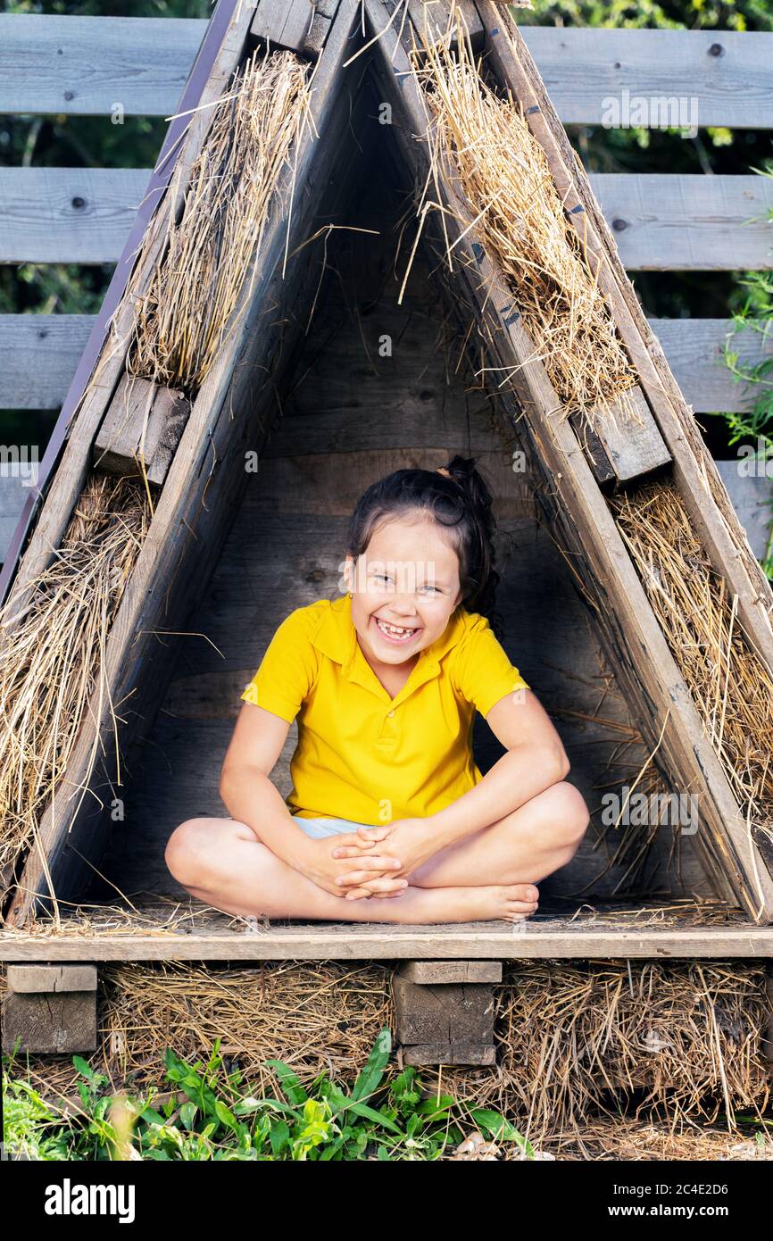 a girl in a bright yellow tshirt sits in a small hut Stock Photo Alamy
