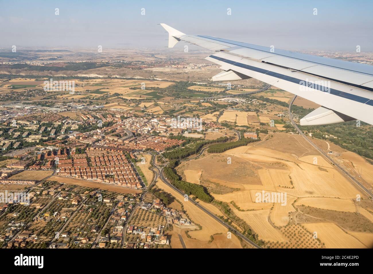 Looking through aircraft window during flight. Aircraft wing over blue skies and cityscape  .Copy space. Stock Photo
