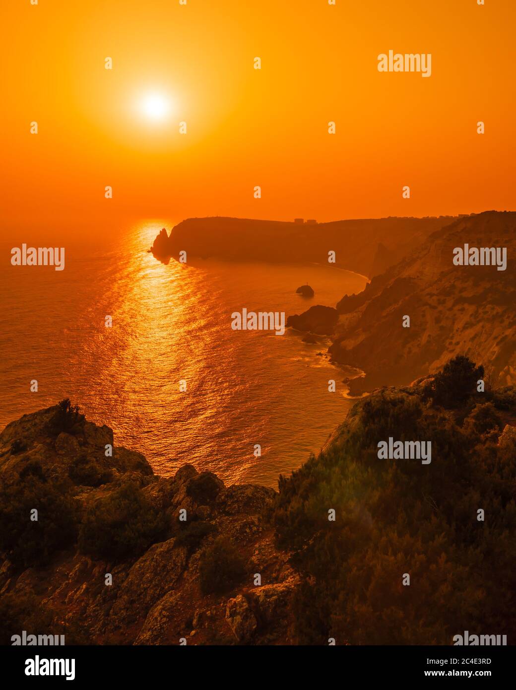 A red burning sunset with the silhouett of a cliff over the sea Stock ...