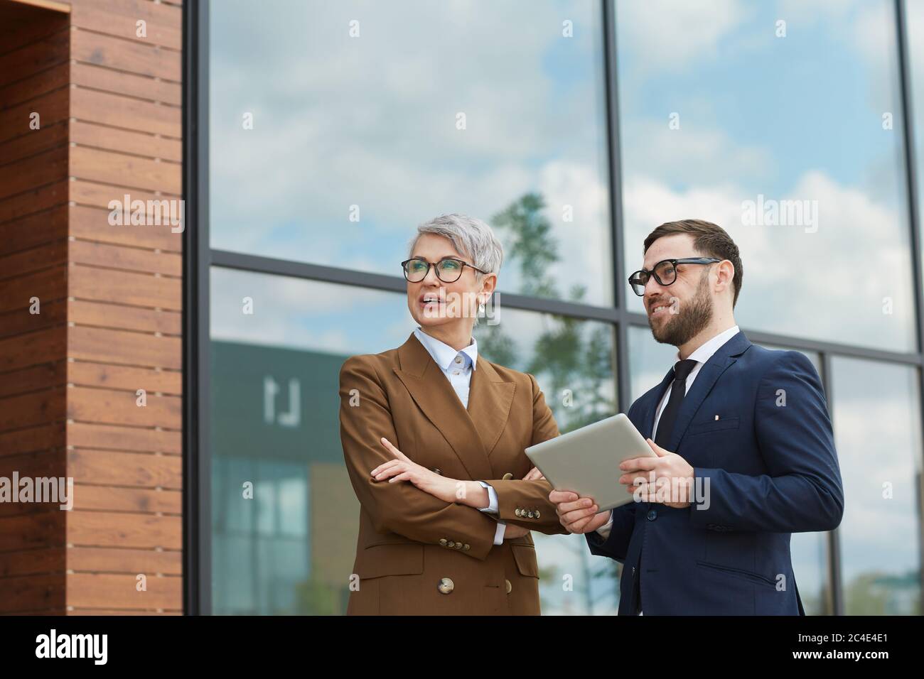 Business colleagues talking to each other while standing outdoors and using digital tablet Stock Photo