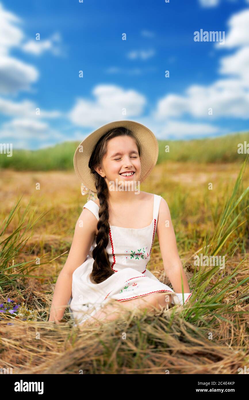 a girl with long hair is sitting on the hay in a straw hat Stock Photo ...