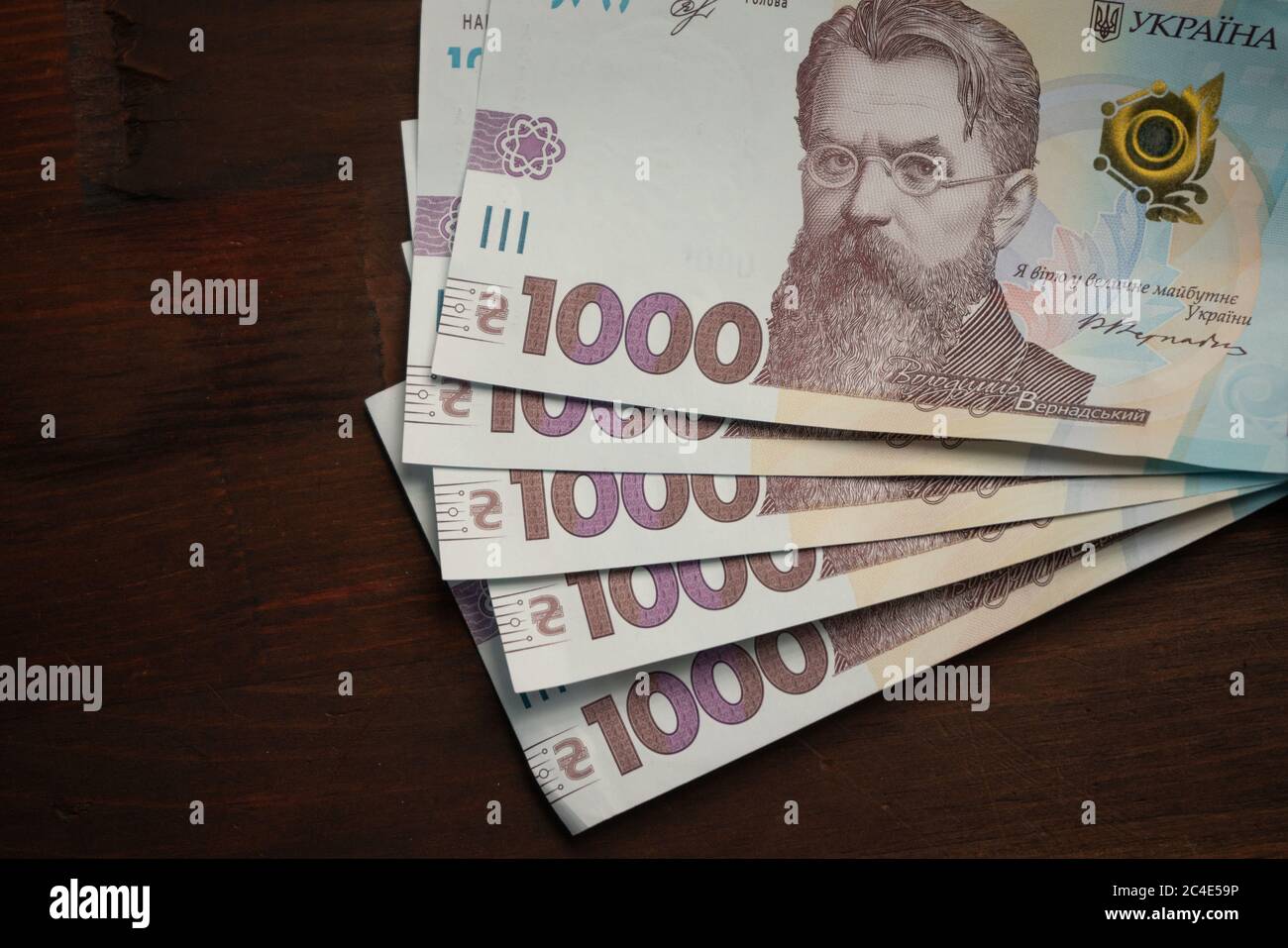 New Ukrainian paper money 1000 hryvnia face value on wooden table with emty cpace for text at left. Close up shot. High angle view Stock Photo