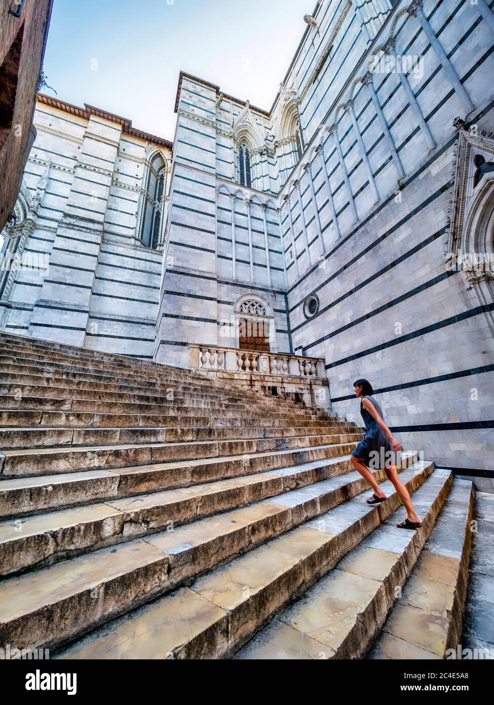 Caucasian female tourist ascending marble steps outside Siena Cathedral Bapistery. Italy. Stock Photo