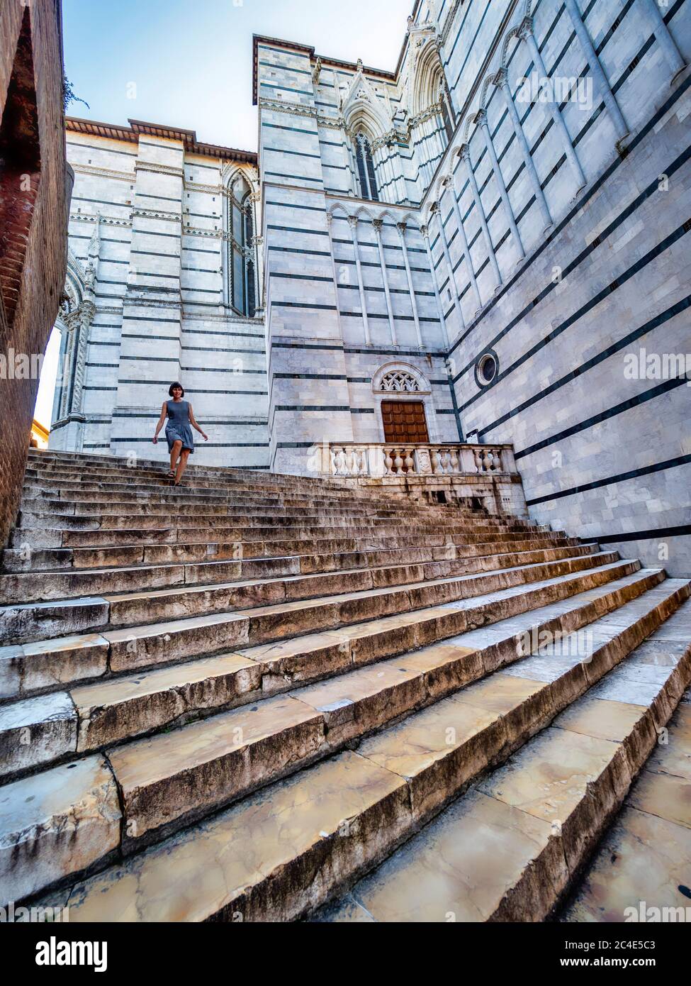 Caucasian female tourist descending marble steps outside Siena Cathedral Bapistery. Italy. Stock Photo