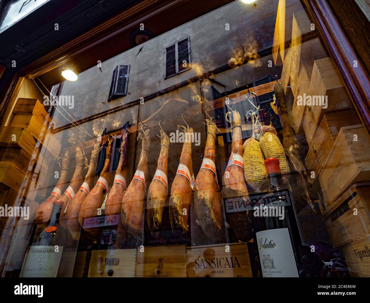 Cured hams hanging in a shop window display in Siena. Italy. Stock Photo