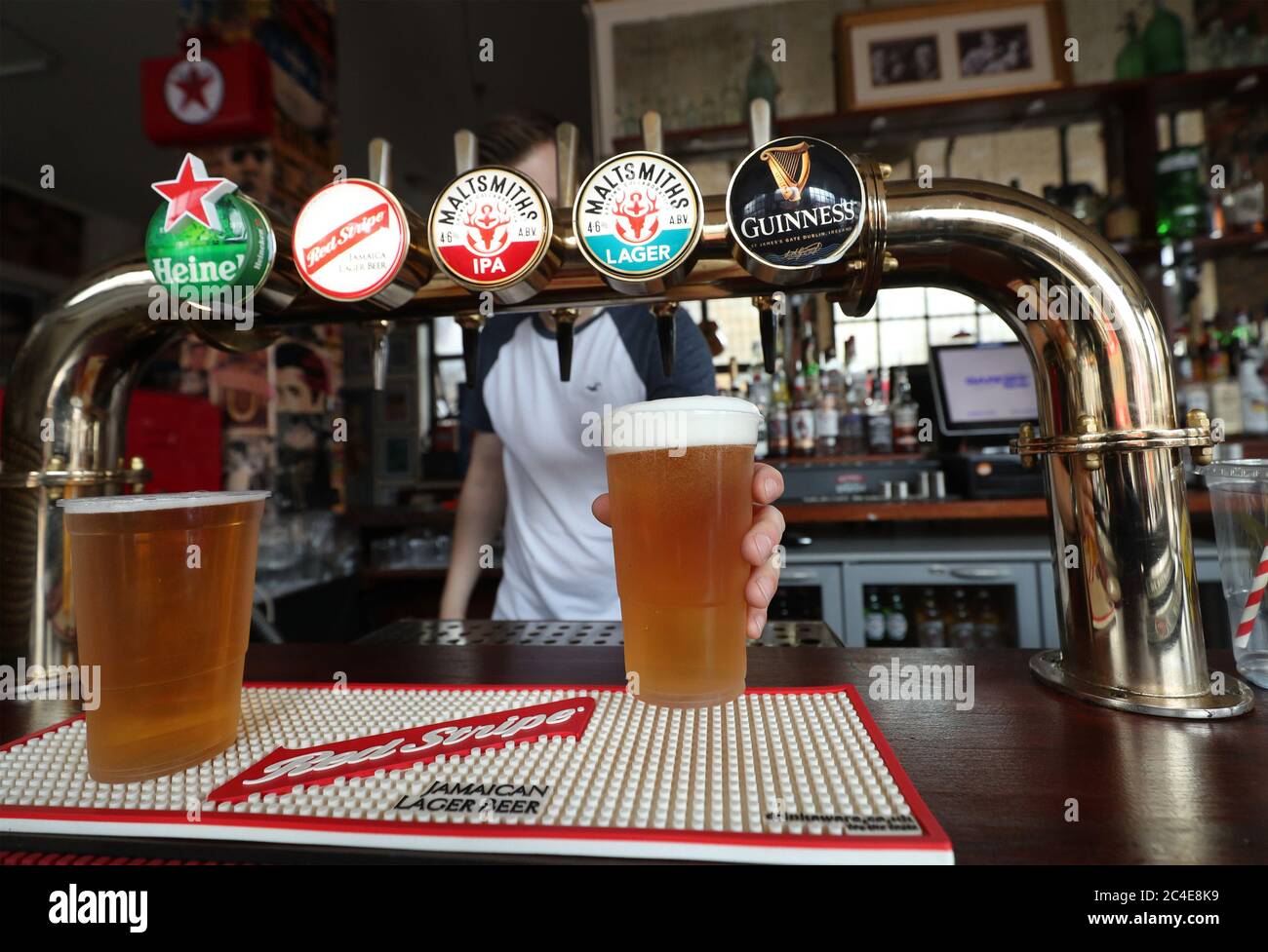 A barman serving takeaway drinks at Charrington's Noted Ales And Stout pub in London, as further coronavirus lockdown restrictions are lifted in England. Stock Photo
