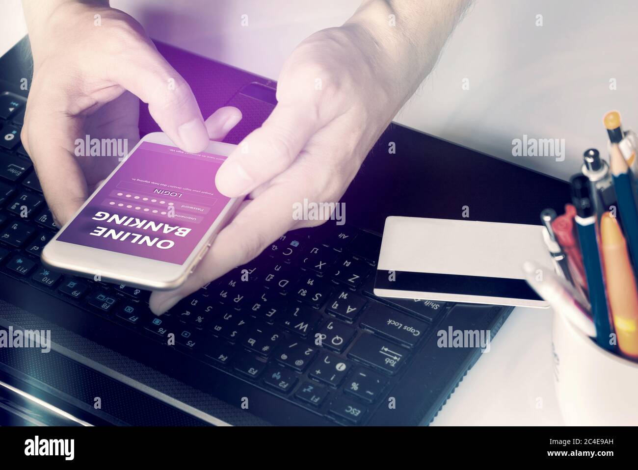 Man's hands using online banking and login username and password with smartphone on desk at home. Stock Photo