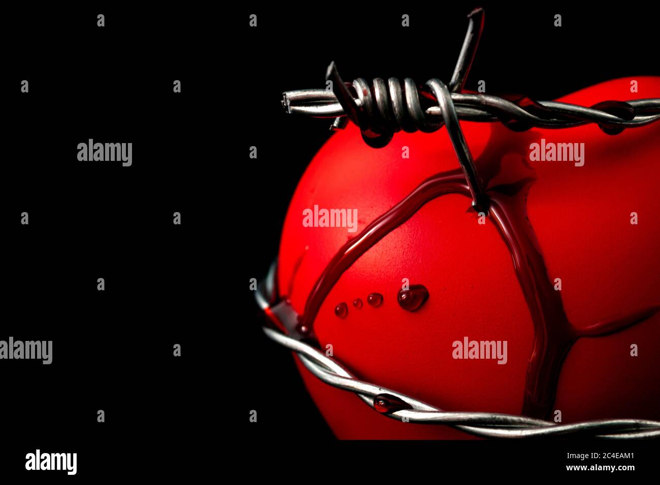 Feeling the heartache, a wounded soul, help with depression and broken hearts concept with barbwire piercing a red heart and blood coming out of the w Stock Photo