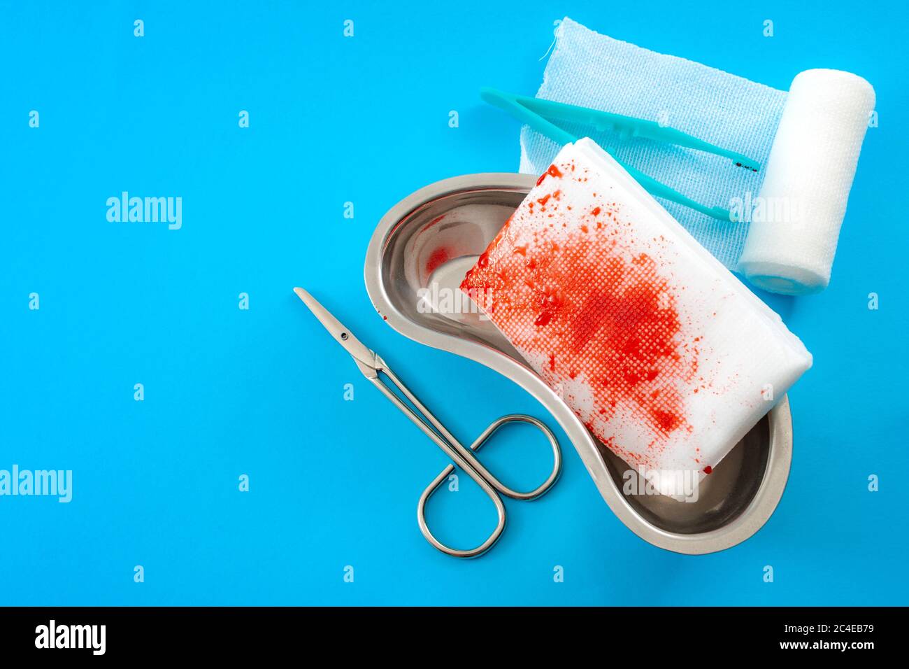 Medical waste, used surgery supplies and first aid concept with roll of gauze bandages, kidney dish, scissors and bloody used bandage covered in blood Stock Photo