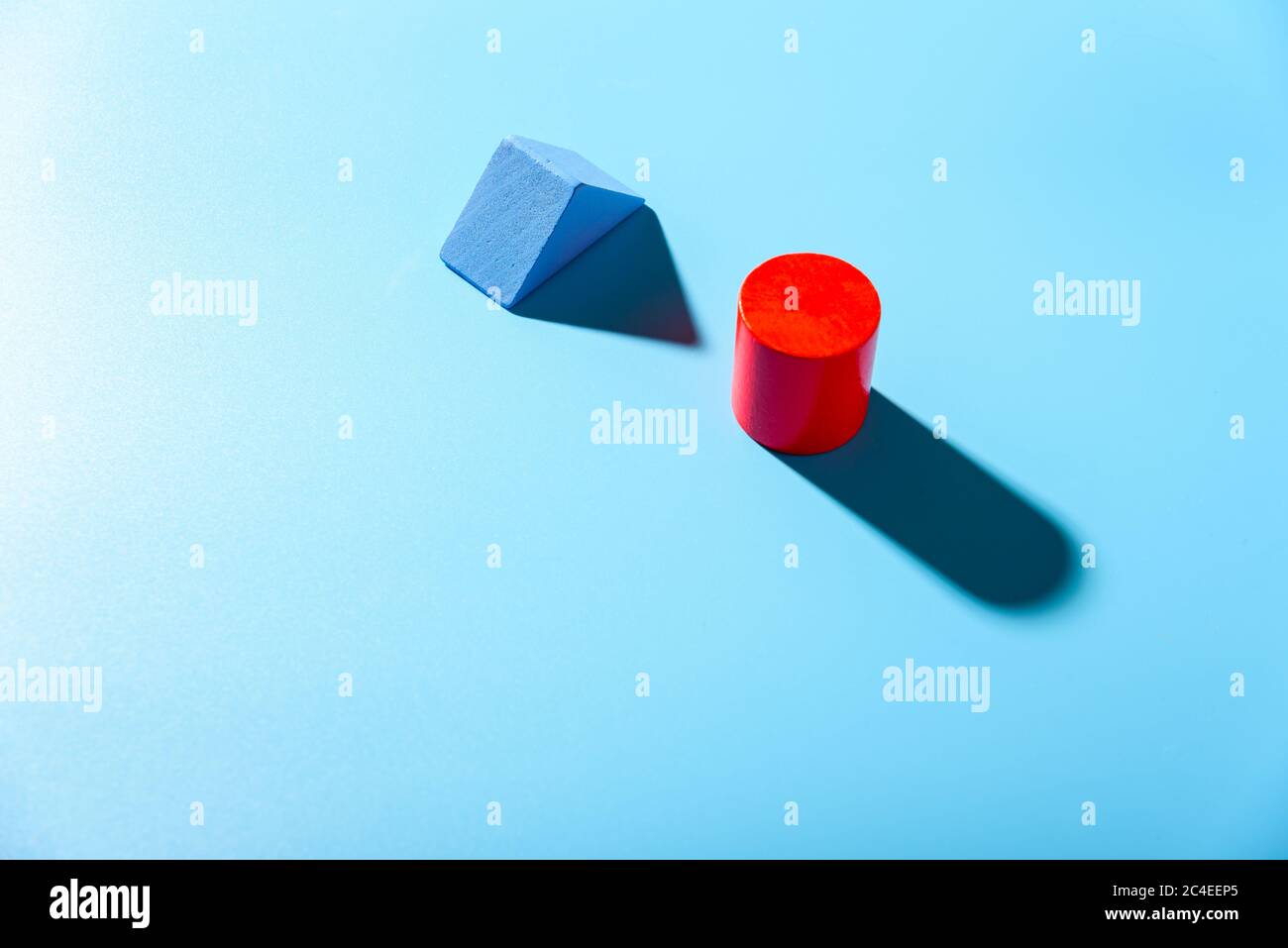 Blue background with red geometric figures casting shadows in a simple composition. Stock Photo