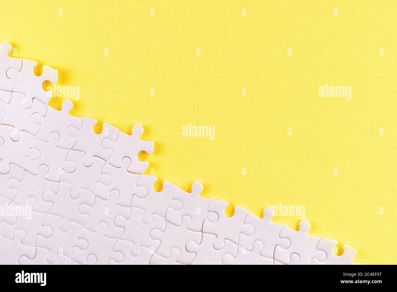 White jigsaw puzzle pieces on yellow. Abstract background with copy space Stock Photo