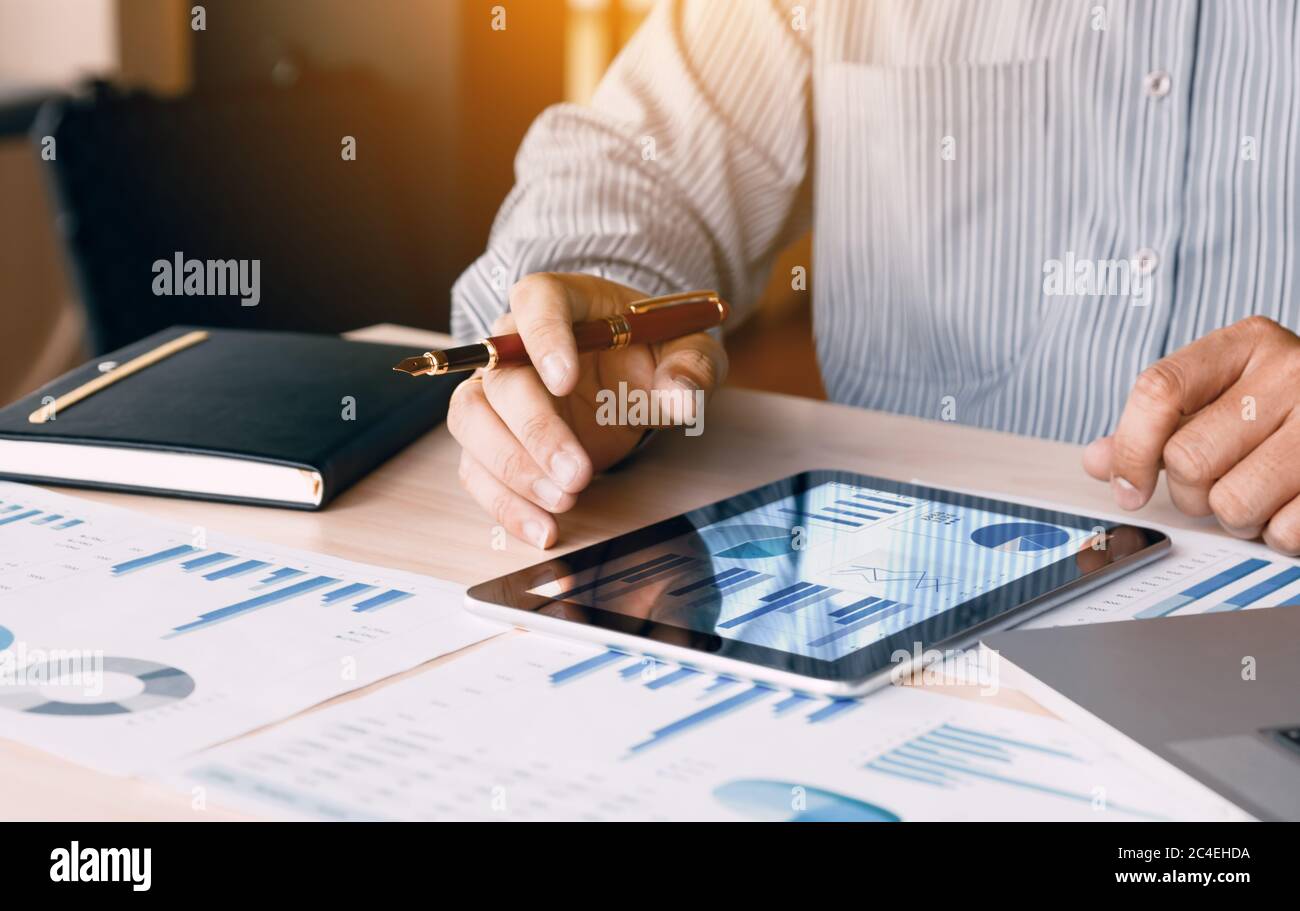 Businessman looking graph and summary report on digital tablet screen with analysis data result. Stock Photo