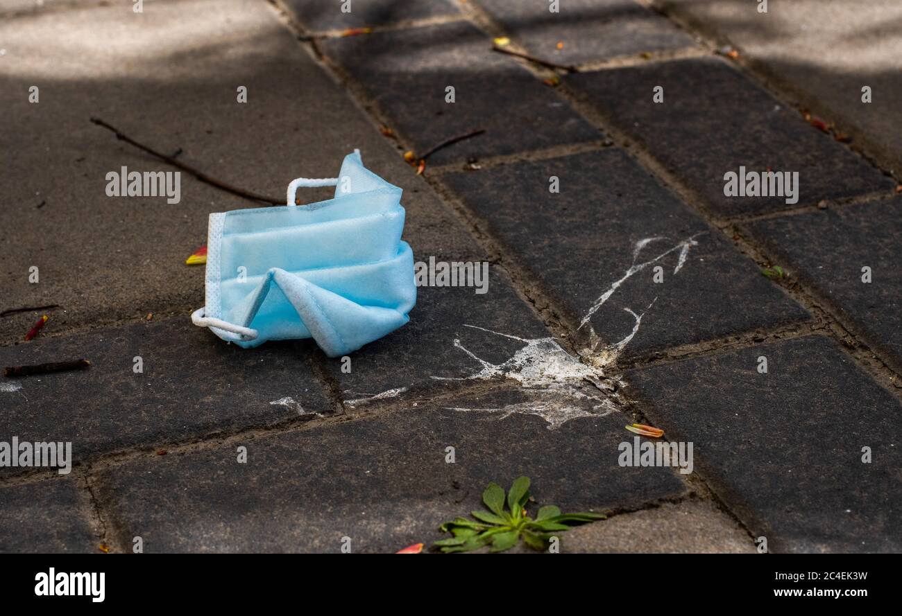 Stop Covid 19. The end of coronavirus. People discard surgical protective face mask on a public streets. Dirty used medical mask laying on the ground Stock Photo