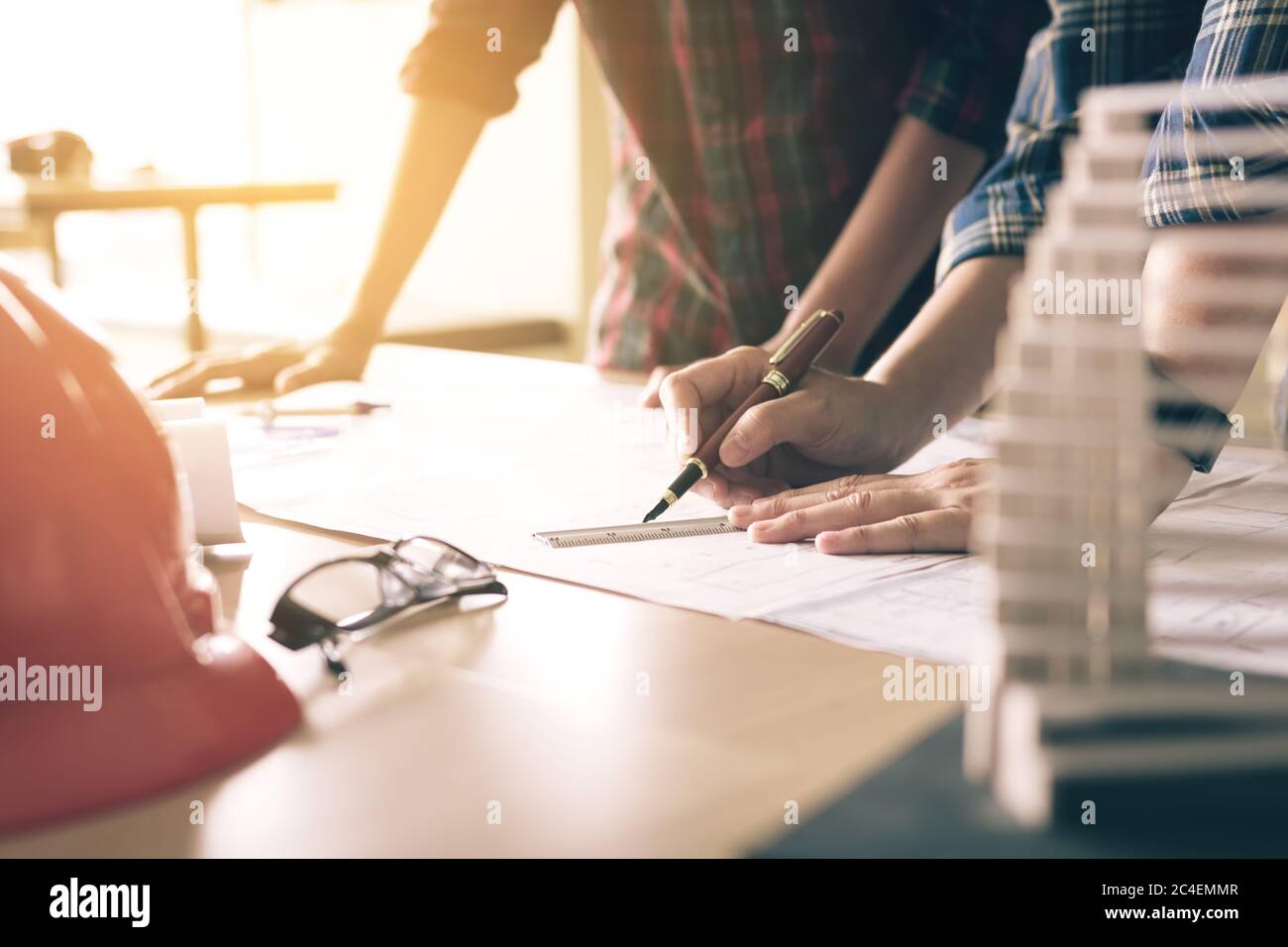 Two architects working with blueprints and discussing project at the meeting in the office. Stock Photo