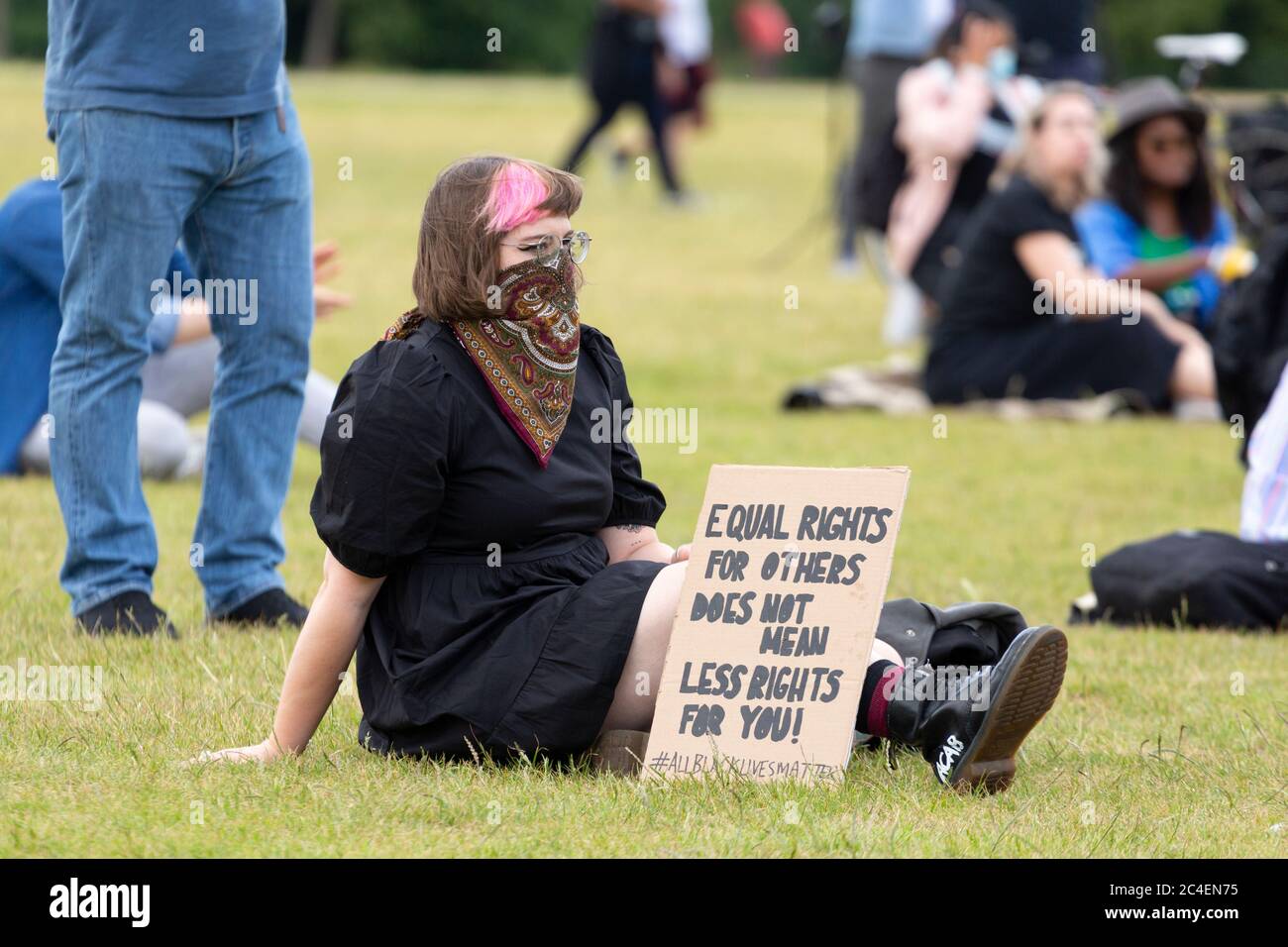 Portrait of a girl sitting on the grass with a protest sign during a Black Lives Matter demonstration, Hyde Park, London, 20 June 2020 Stock Photo