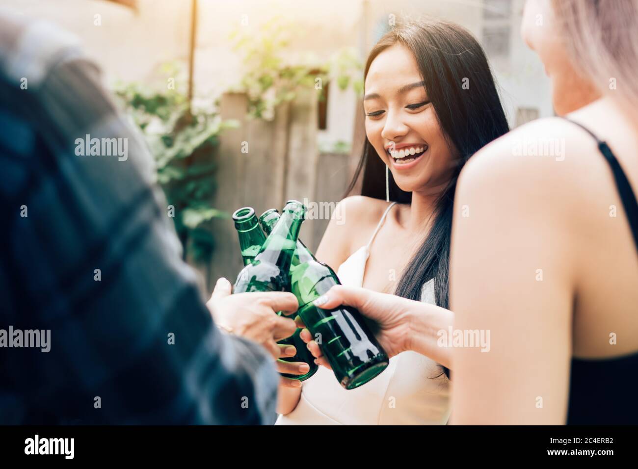 Asian group enjoying toasting drinks party with clinking beer bottle. Stock Photo