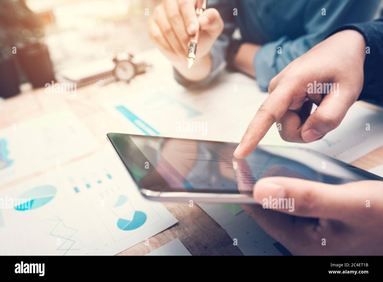 Business people pointing chart on tablet screen with analysis together ...