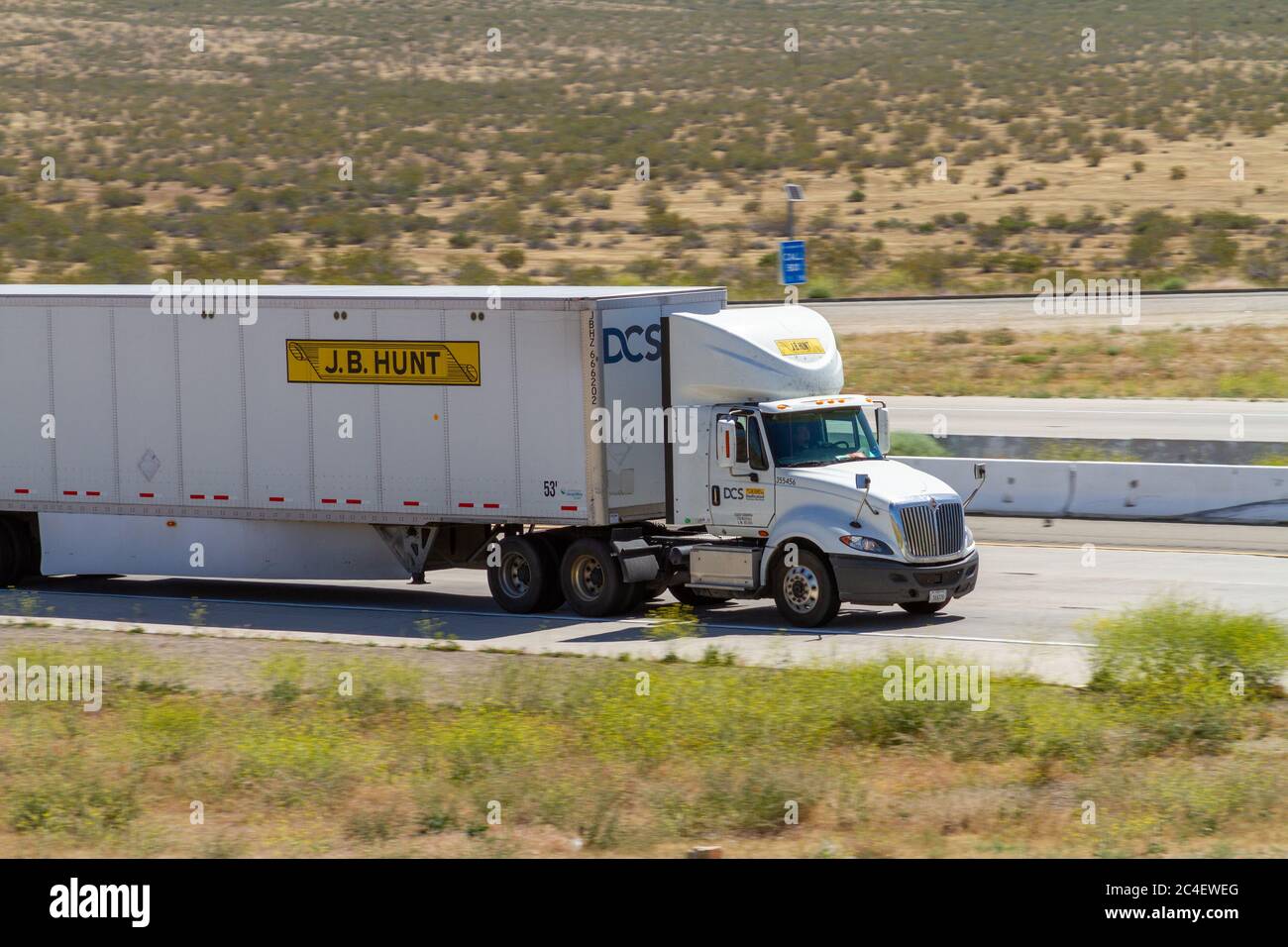 Apple Valley, CA / USA – May 16, 2020: White J.B. Hunt semi-truck on Interstate 15 in the Mojave Desert near the Town of Apple Valley, California. Stock Photo