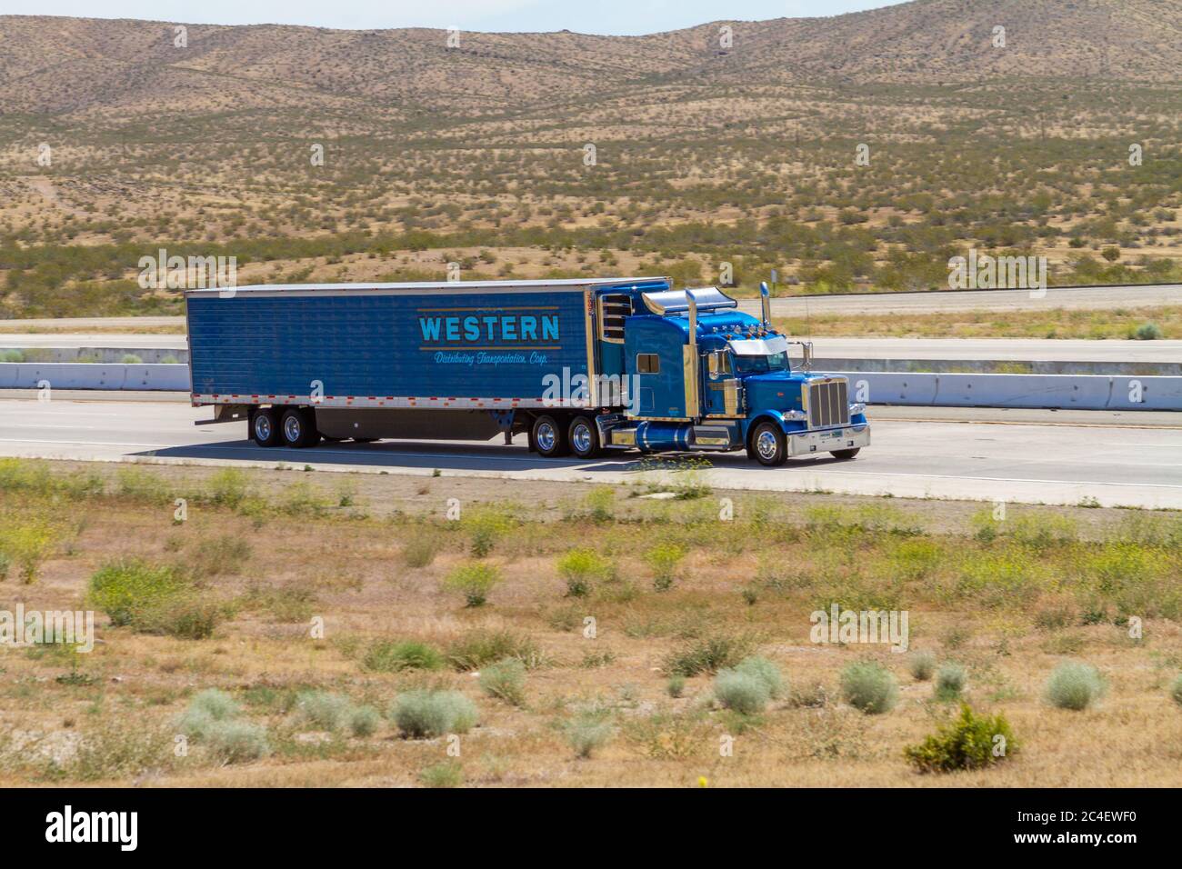 Apple Valley, CA / USA – May 16, 2020: Blue Western Distributing Transportation, Corp, semi-truck on Interstate 15 in the Mojave Desert near the Town Stock Photo