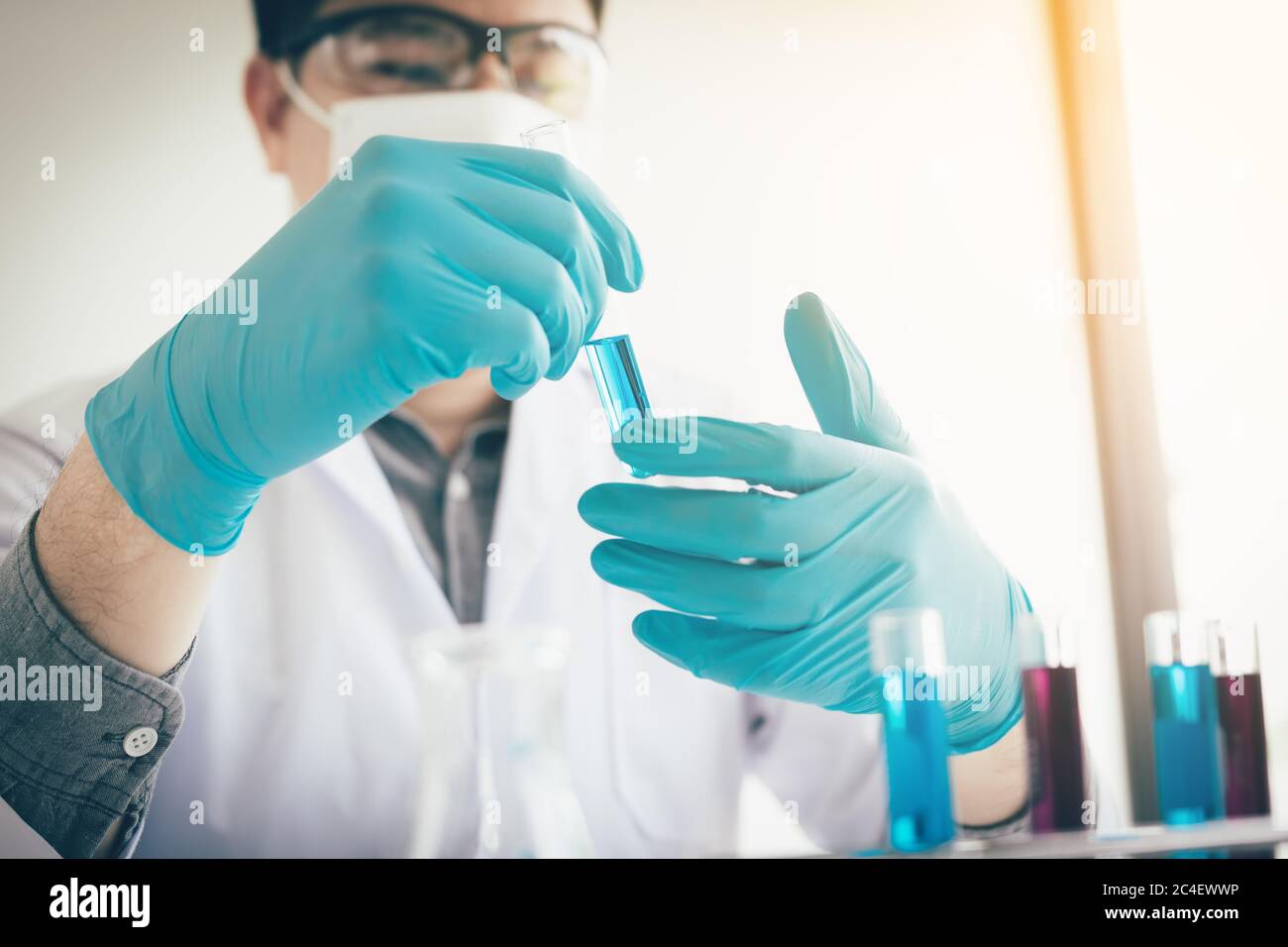 Asian scientist shaking and analyzing a liquid solution in lab. Stock Photo