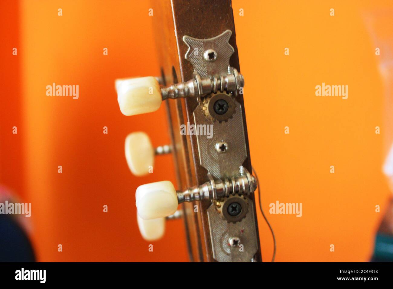 headstock with mechanics of a classical guitar with bright orange background Stock Photo