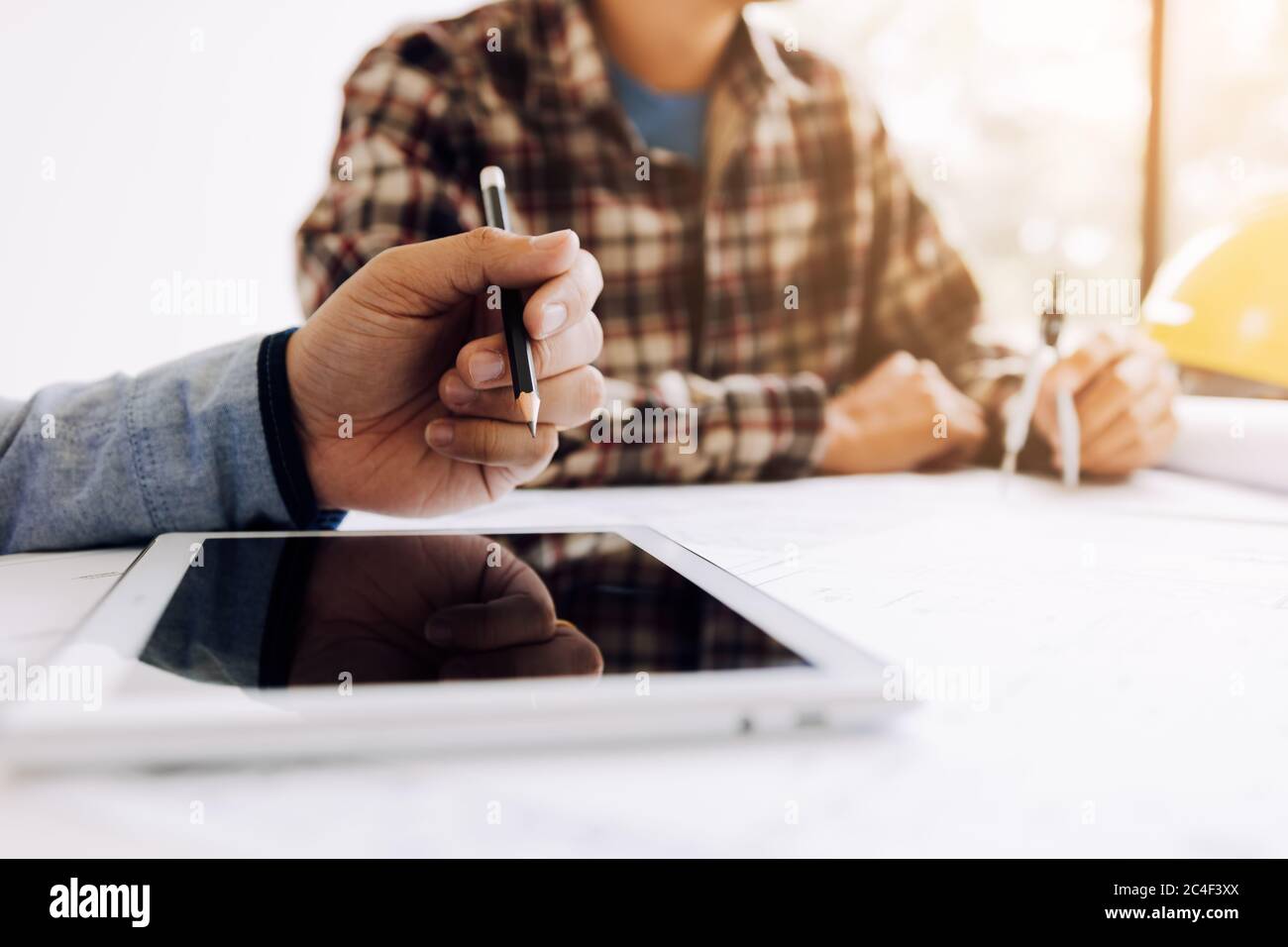 Male engineering using digital tablet with architectural plan on desk. Stock Photo