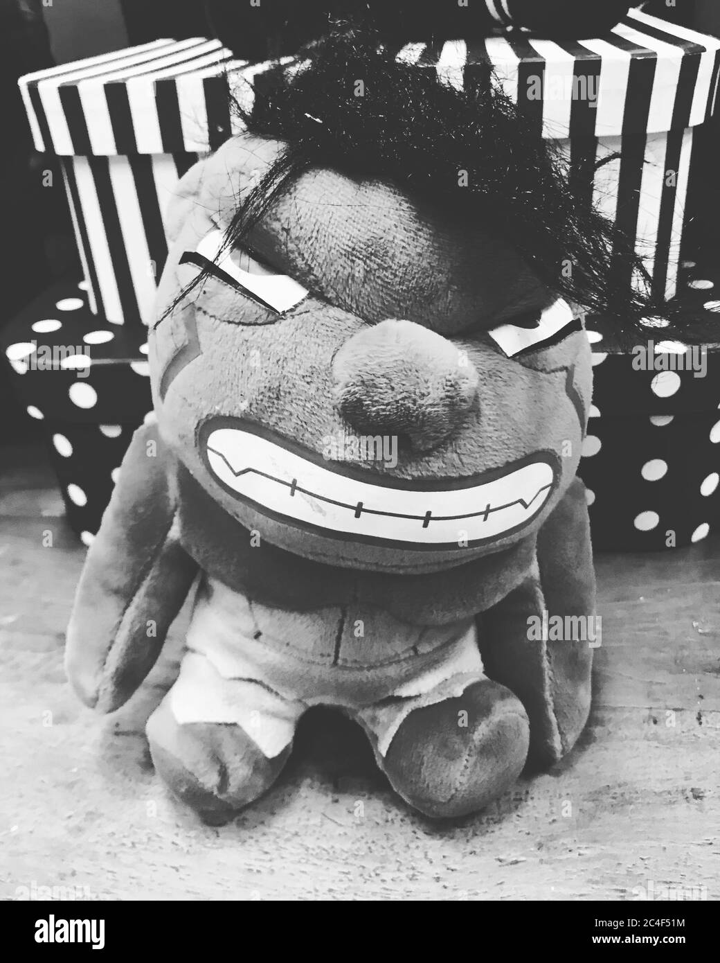 Black-and-white shot of a toy with angry face and some present boxes in the back Stock Photo