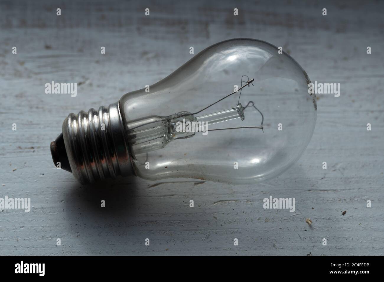 Burned out old light bulb lying on the wooden painted white surface