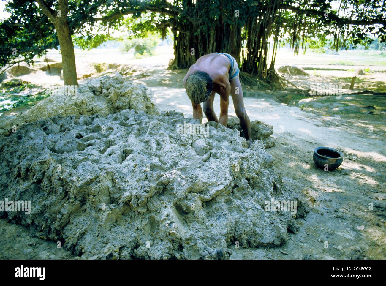 A man moulds clay collected to make earthenware. Fine clay is used in making pottery, which is an age-old profession in Bangladesh. Stock Photo