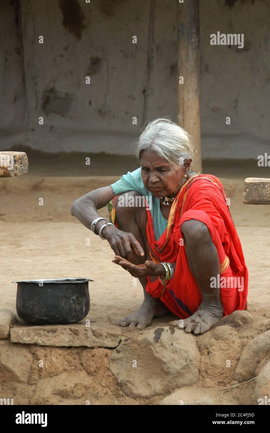 An elderly woman making a paste made from local herbs to clean her teeth. Medical services are rather poor and insufficient in villages such as this o Stock Photo