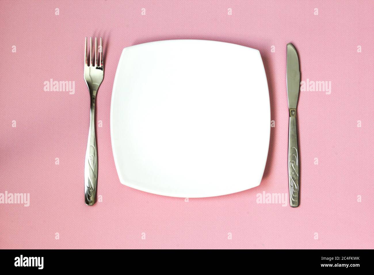 Empty plate, fork and knife over pink background. Clean plate and ...