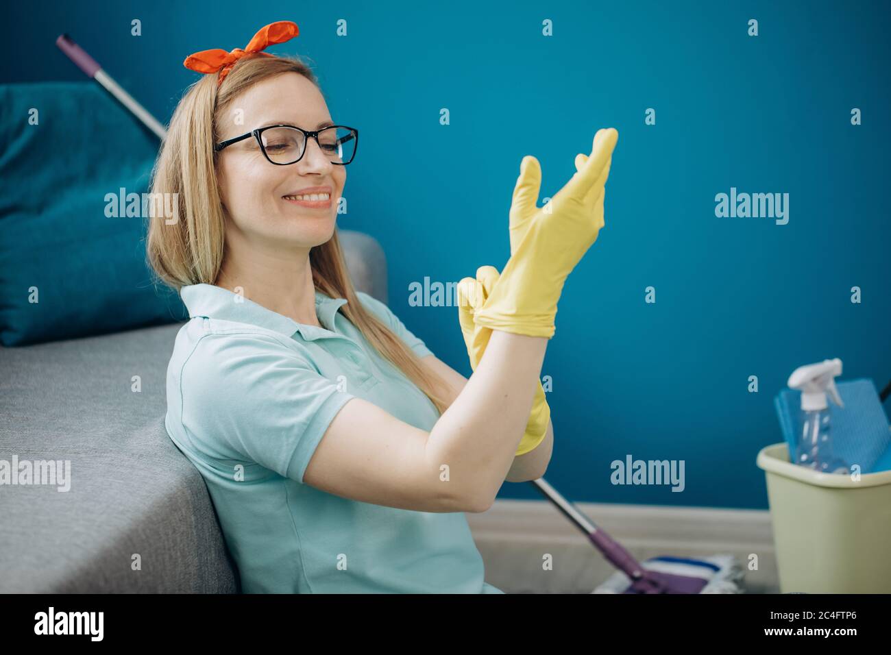 Happy woman putting on yellow rubber gloves before cleaning Stock Photo ...