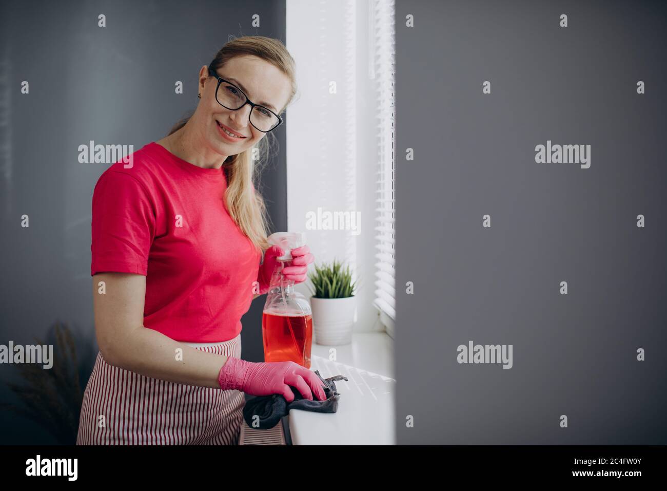 Woman using cloth and spray for cleaning windowsill Stock Photo