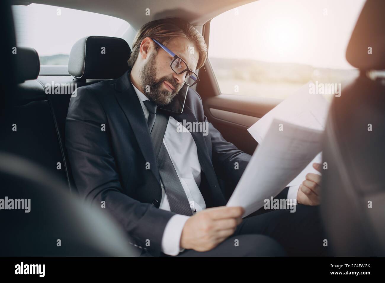 Man sitting in car with documents and talking on mobile Stock Photo