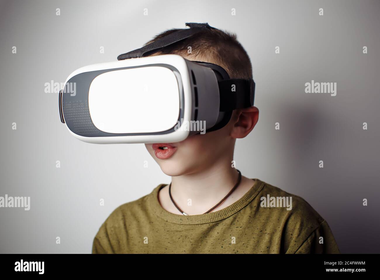 Boy playing mobile game app on device virtual reality glasses on white background. Boy action and using in virtual headset, VR box for use with smart Stock Photo