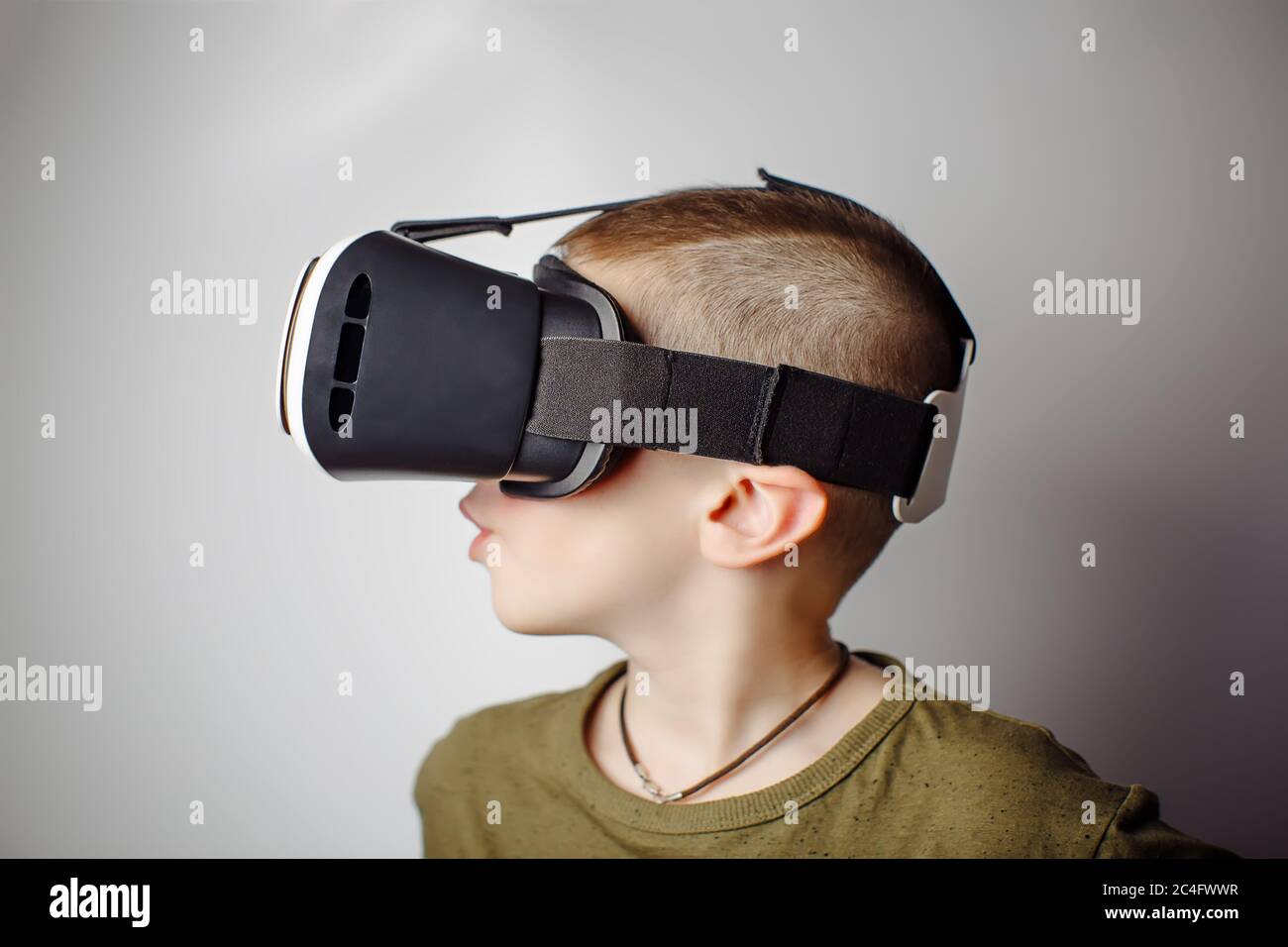 Boy playing mobile game app on device virtual reality glasses on white background. Boy action and using in virtual headset, VR box for use with smart Stock Photo