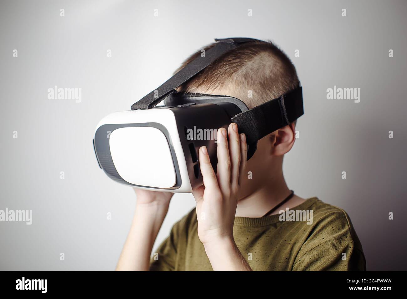 Boy playing mobile game app on device virtual reality glasses on white background. Boy action and using in virtual headset, VR box for use with smart Stock Photo