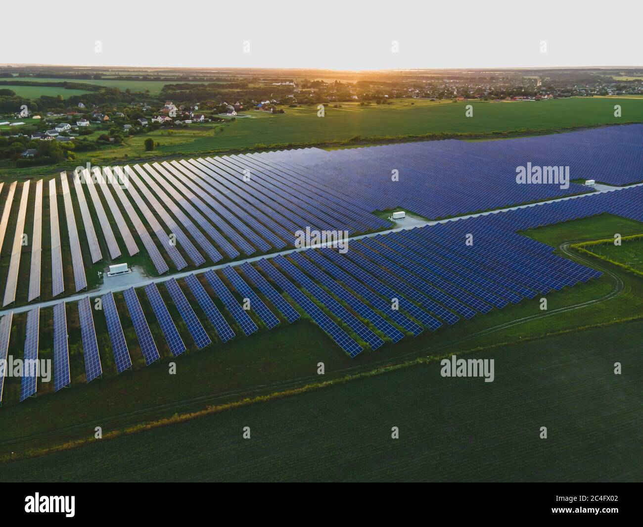 Aerial drone view of large solar panels at a solar farm at bright summer sunset. Solar cell power plants, colorful photo Stock Photo