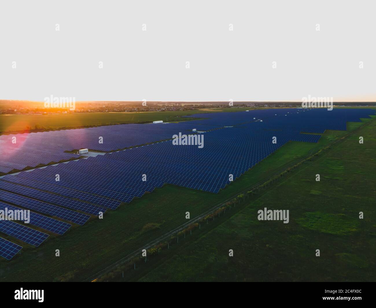 Aerial drone view of large solar panels at a solar farm at bright summer sunset. Solar cell power plants, colorful photo Stock Photo